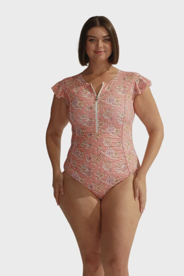Brunette model wearing pink floral zip front frill sleeve one piece
