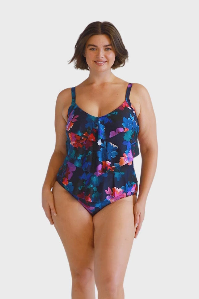 brunette plus size model wears navy blue floral 3 tier ruffle one piece swimsuit