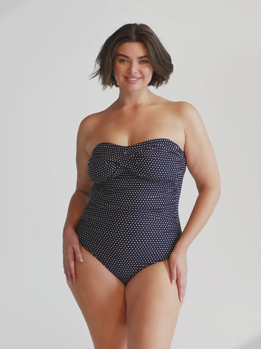 model wearing navy and white dots twist front bandeau one piece