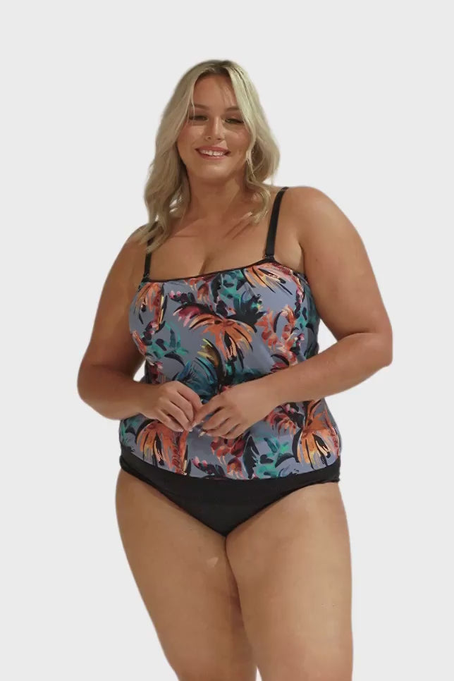 Model wearing blue-grey tropical print flouncy tankini and black bottoms