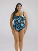 Brunette model in studio wearing a floral blue tank one piece