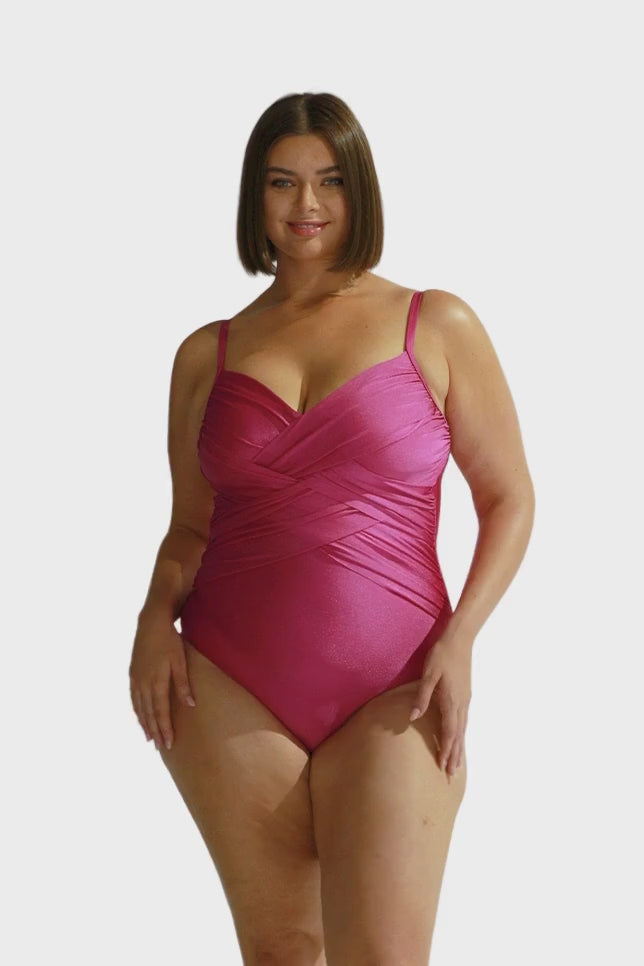 Brunette size 16 model wears metallic pink criss cross one piece with v neckline and adjustable straps