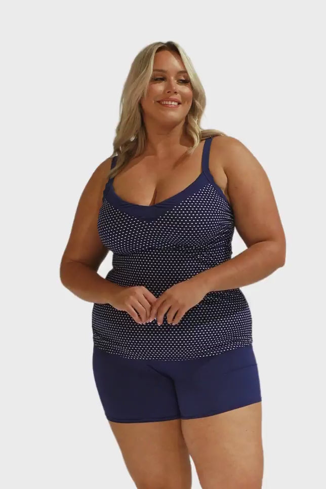 Model wearing navy boyleg shorts with navy dots tankini