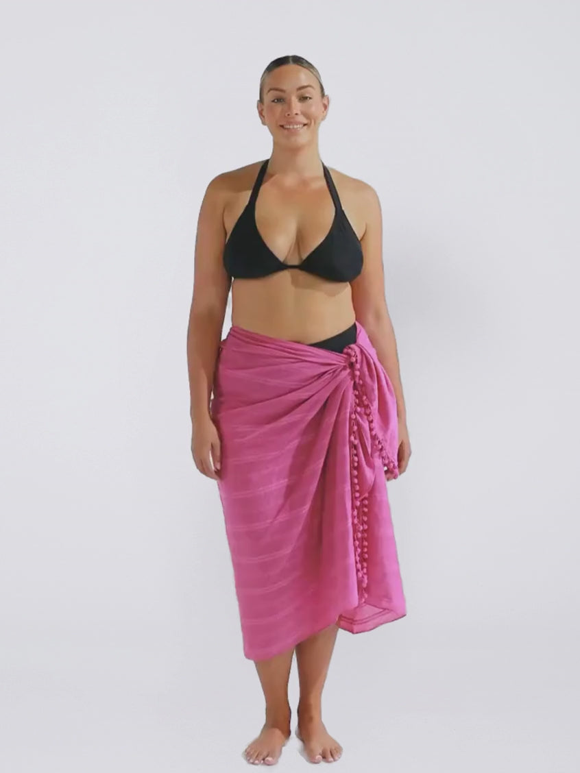 Model in studio wearing a plum cotton sarong with pom poms