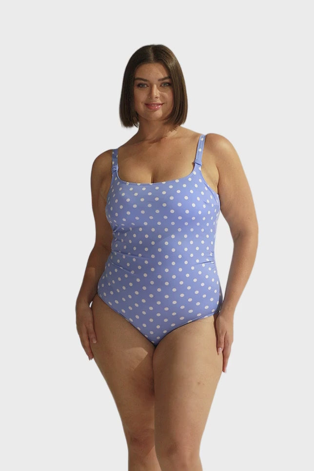Brunette model wearing chlorine resistant light blue with white polka dots one piece swimsuit