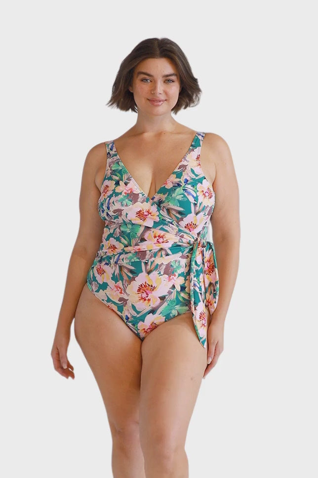 Brunette model wearing womens green floral crossover one piece swimsuit