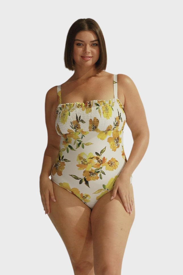 Brunette model wears white and yellow floral shirred one piece