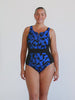 Blonde model wearing a sleeveless zip front one piece in blue and black chlorine resistant