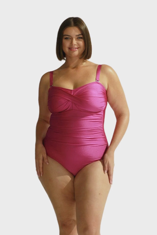 Brunette model wears hot pink twist front bandeau one piece with shelf bra and removable straps