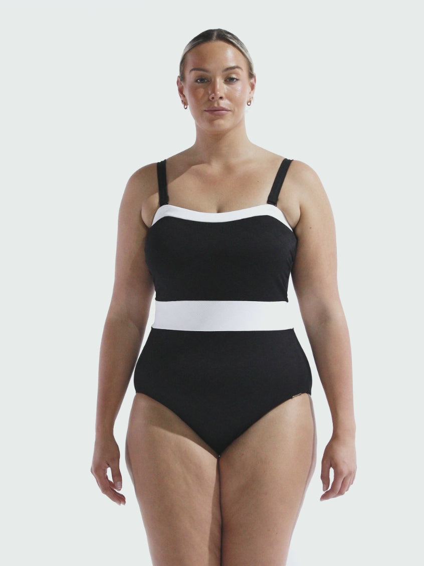 Video of model in studio wearing a black and white textured one piece with removable straps