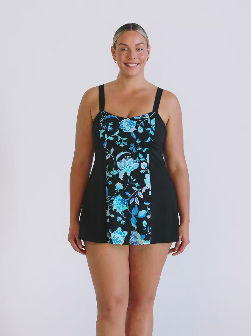 Blonde model in studio wearing a wide strap swim dress in floral blue and black chlorine resistant