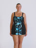 Blonde model in studio wearing a wide strap swim dress in floral blue and black chlorine resistant