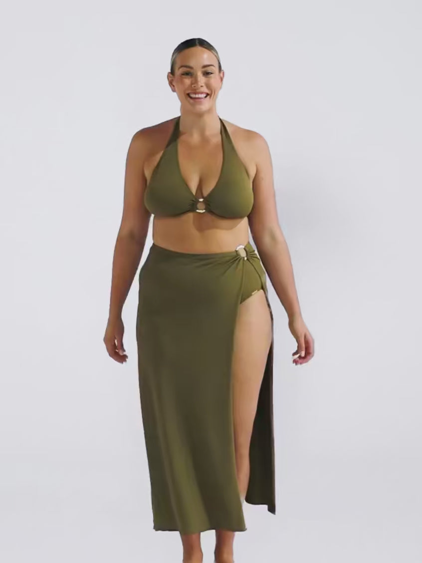 Blonde model in studio wearing a long maxi khaki skirt in a honey comb texture fabric with metal ring