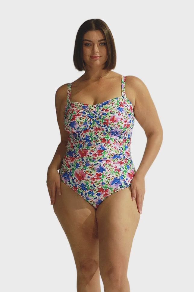 Brunette model wears floral twist front bandeau one piece swimsuit