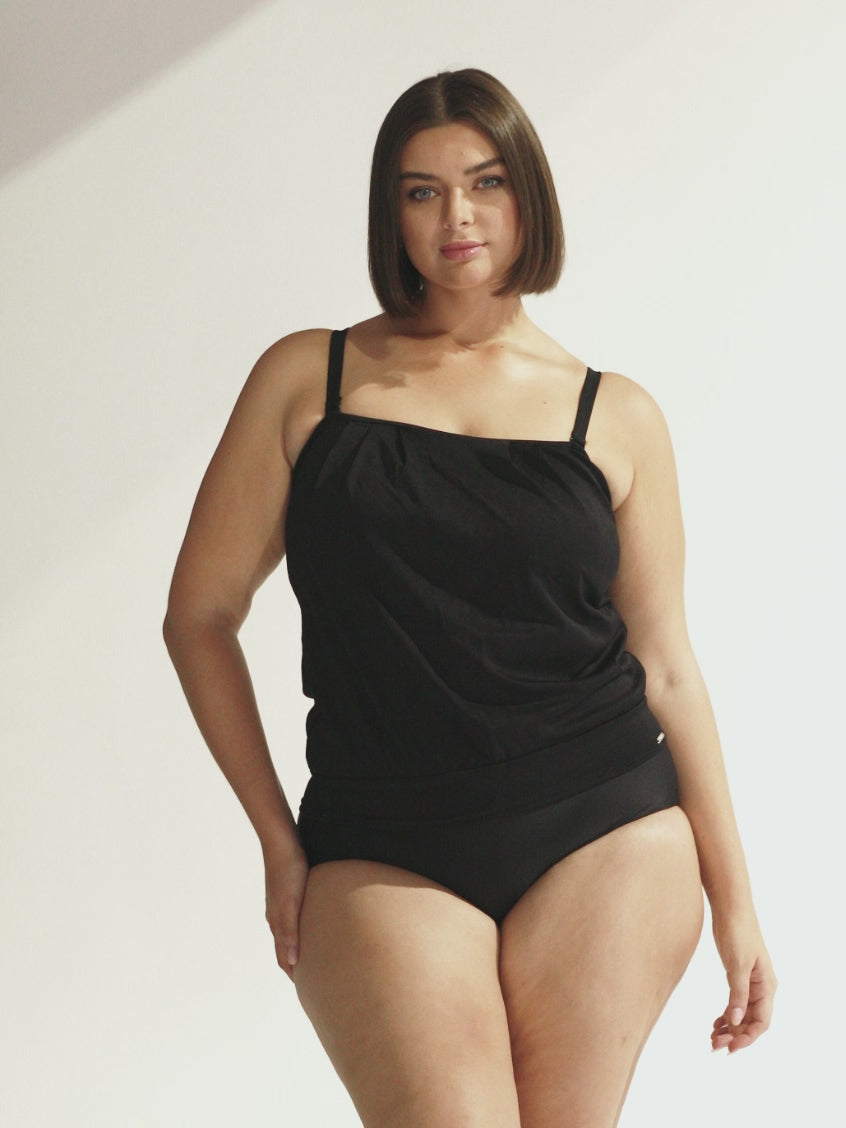 Video of model in studio showing textured tankini top with flouncy bandeu detail