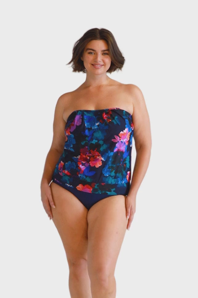 Brunette model wears navy floral flouncy tankini swim top