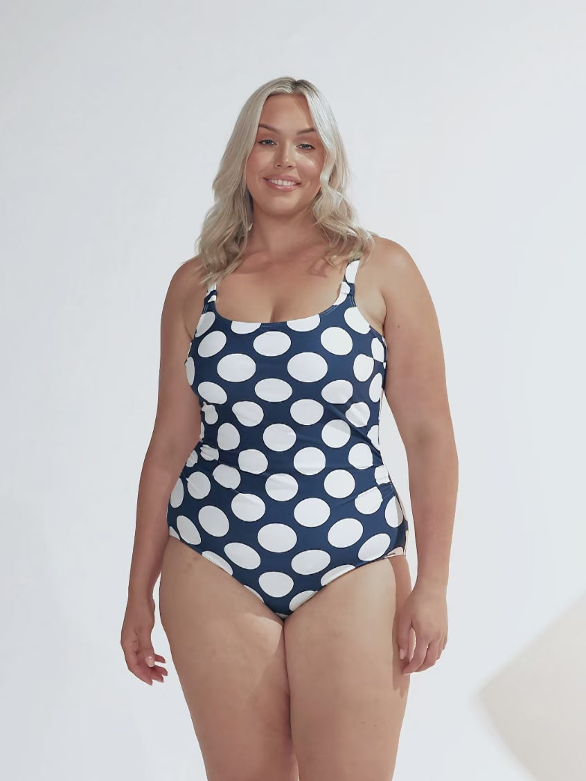 model wearing navy and large white polka dot tank one piece swimsuit