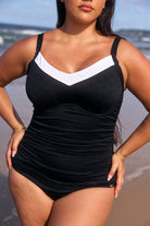 Zoomed in photo of a model wearing the Capriosca Acapulco one piece, which is made from chevron textured fabric. This underwire style is black with a white v-neck.