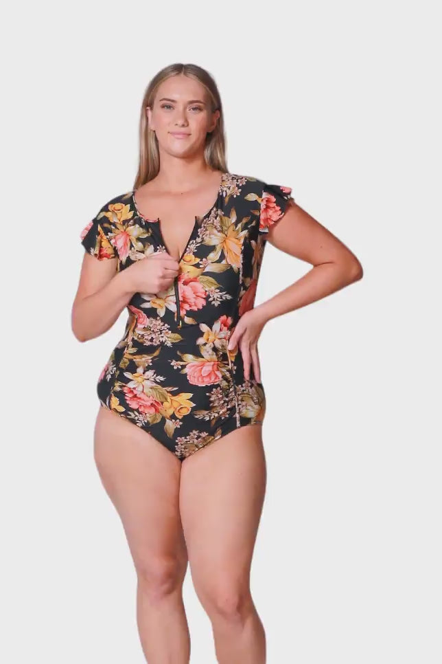 blonde women wearing gold, white and pink floral zip front one piece with frilled cap sleeves for sun protection