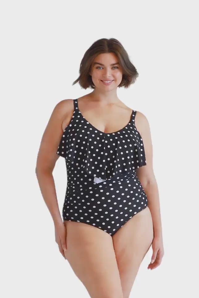 Brunette model wearing black and white dots swimsuit