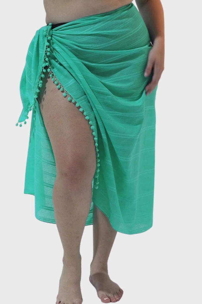Model wearing teal coloured sarong with pompom detail