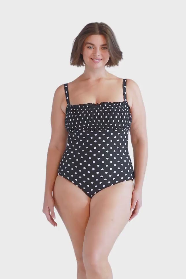 Brunette model wears black and white dots one piece swimsuit