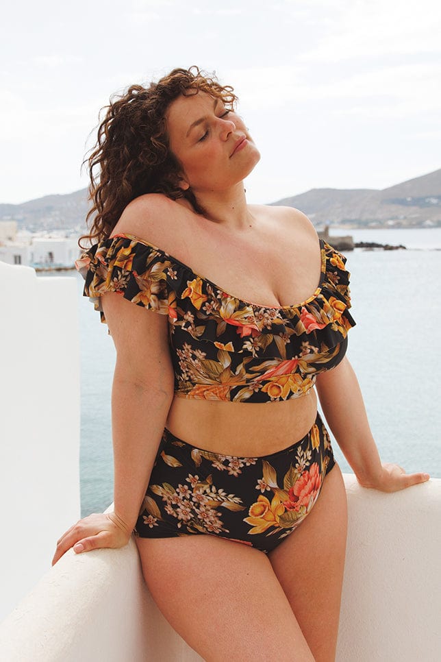 brunette women in greece wears gold and pink floral bikini top with double frill ruffles and a matching high waisted pant