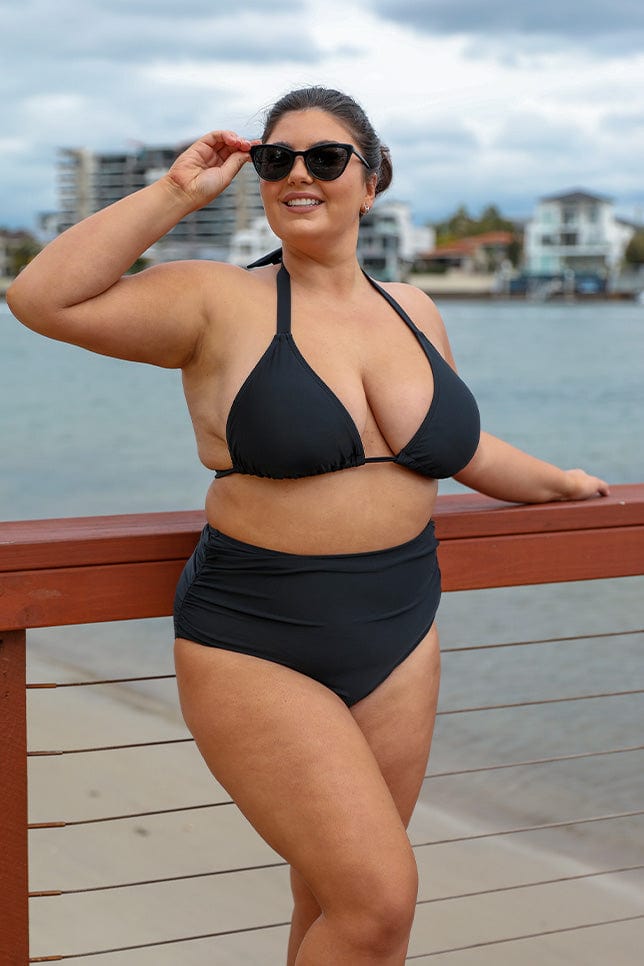 Brunette model wearing black bikini top with high waisted extra ruched bikini bottoms