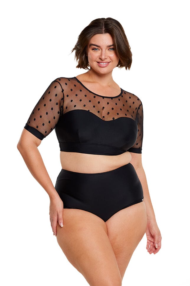 Brunette model wears black polkadot bikini top with mesh short sleeves