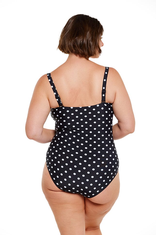 Brunette model wears black and white dots one piece swimsuit