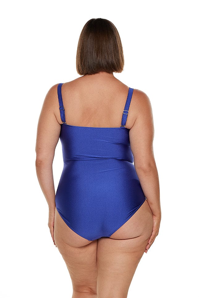 Brunette model wears royal blue metallic twist front bandeau one piece swimwear australia