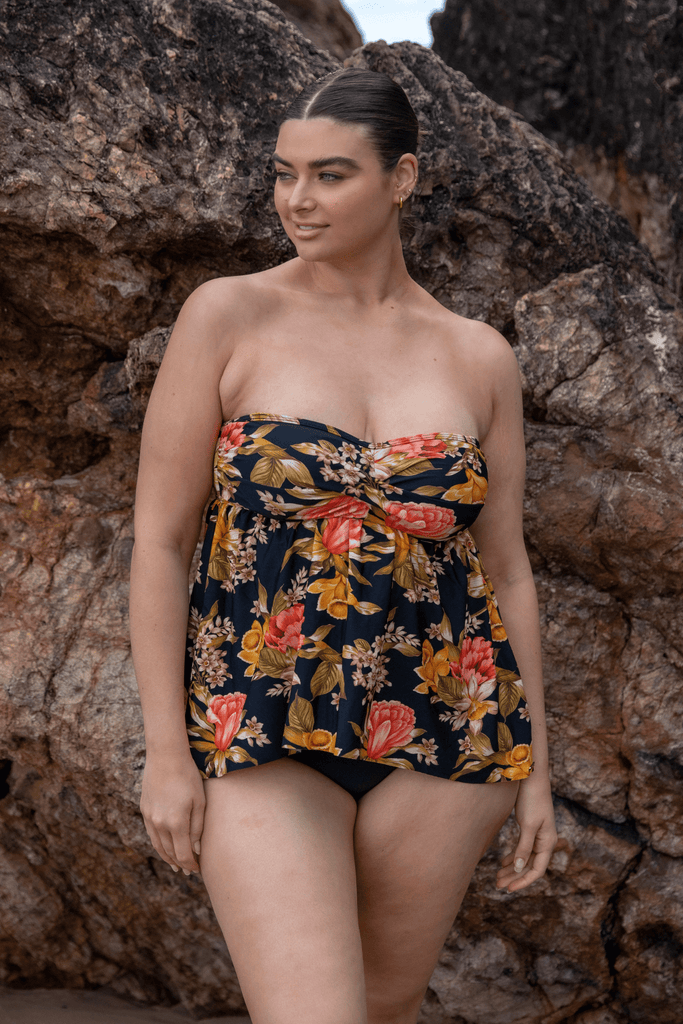 Model wearing a strapless tankini top in black floral print with yellow and orange flowers