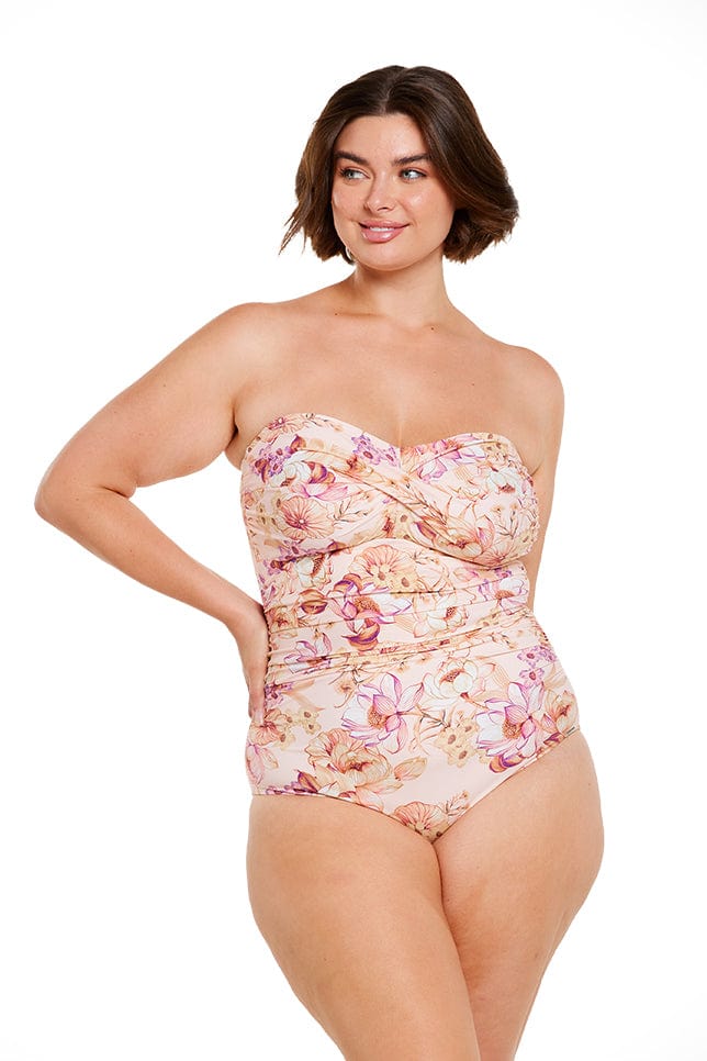 Brunette model wears peach floral strapless bandeau one piece swimsuit