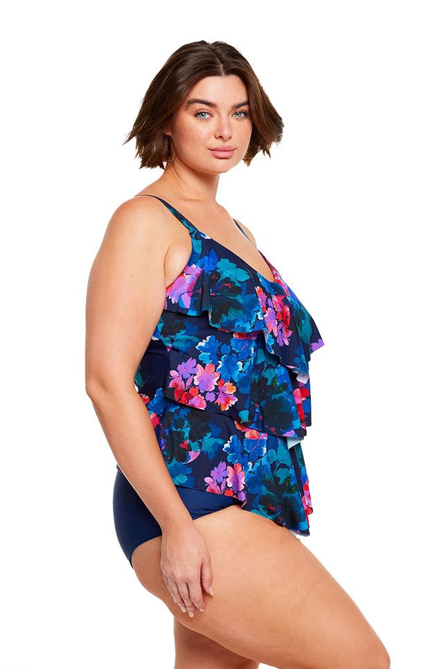 Brunette size 16 women wears flattering navy blue floral ruffle tankini top