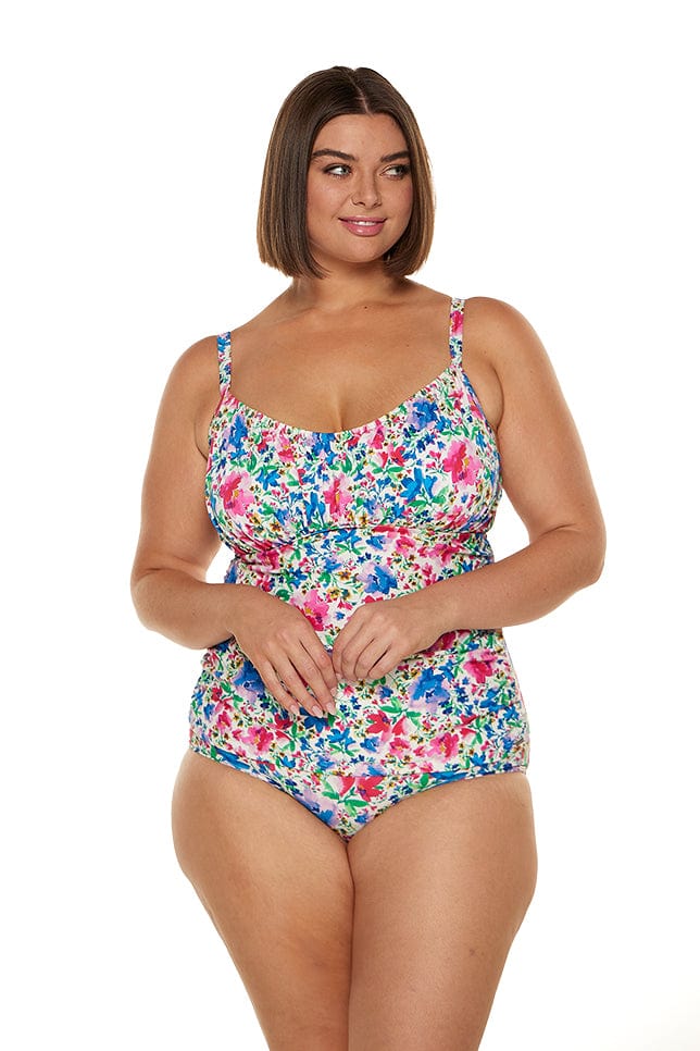 Brunette model wears pink and blue floral ruched tankini top with underwire support
