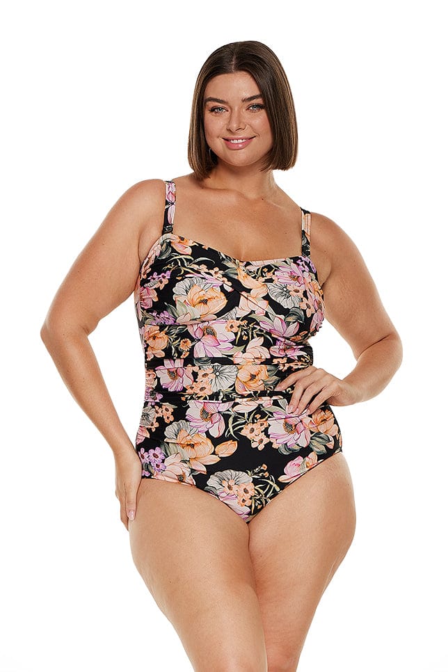 Brunette model wears orange and black floral bandeau one piece with removable straps
