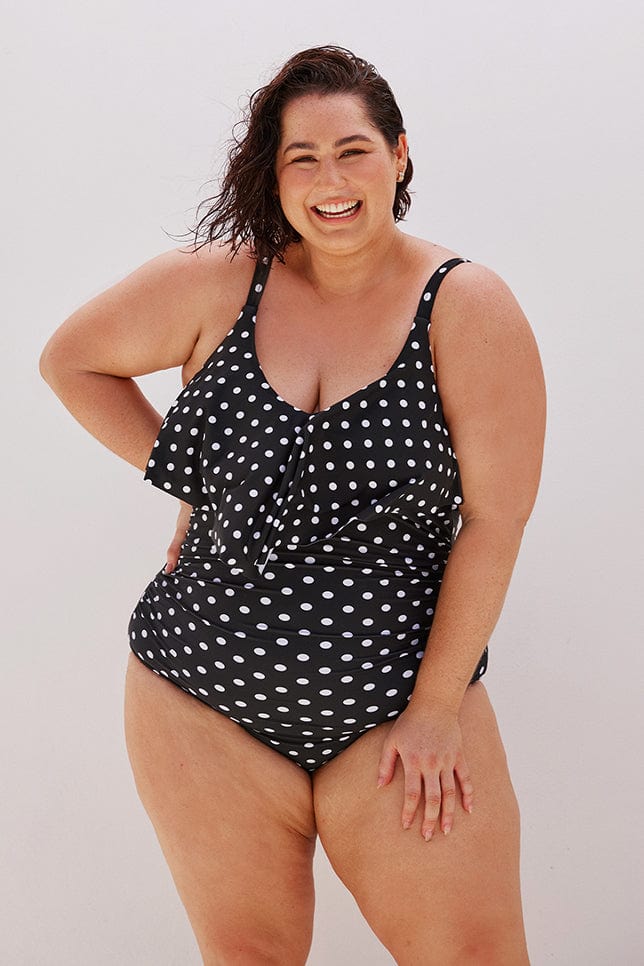 Brunette plus size model wears retro one piece in black and white dots