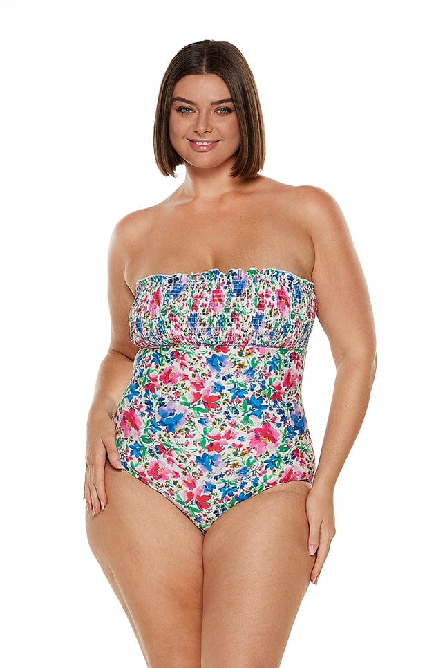Brunette women wears bright floral shirred bandeau one piece with the straps removed