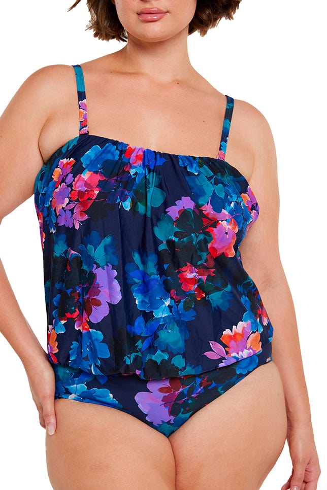 brunette women wears flattering navy blue floral flouncy one piece with removable straps