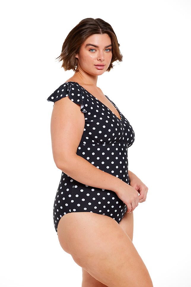 Model wearing frill sleeve black and white spotty swimsuit