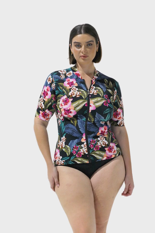 Video of brunette model wearing tropical floral short sleeve rash vest