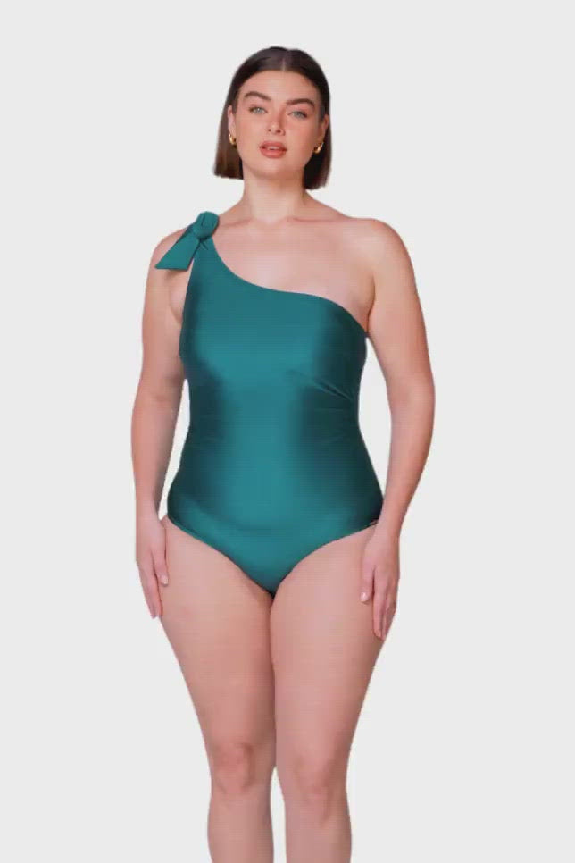 product video of brown haired model wearing a metallic fabric deep teal one piece with adjustable one shoulder strap