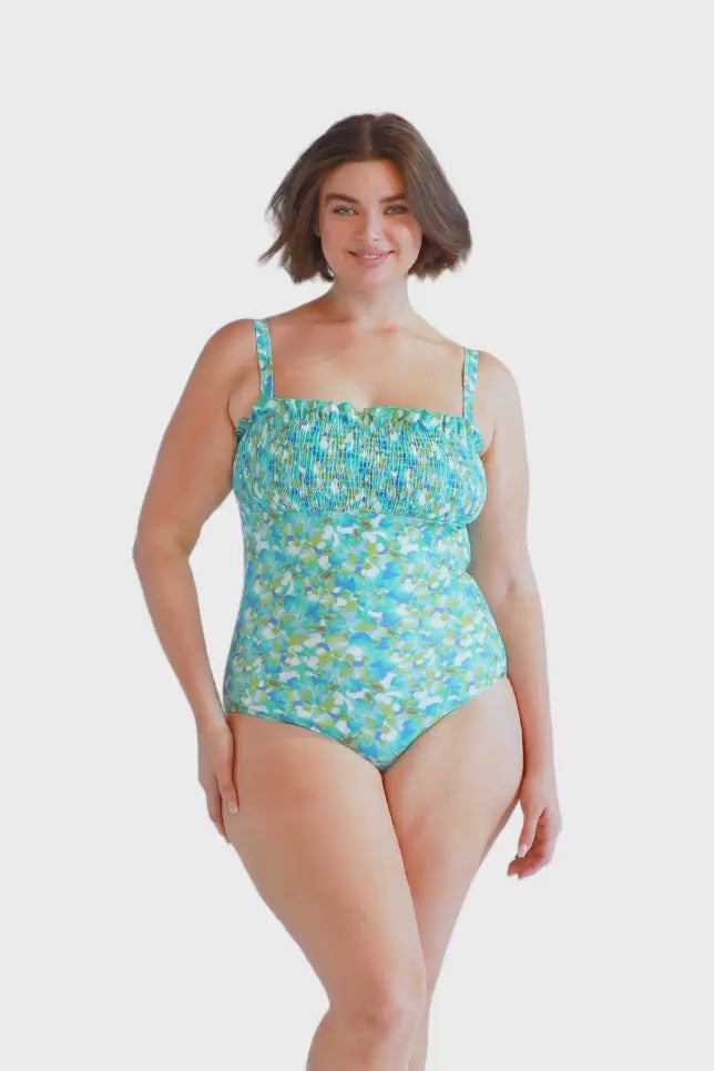 brunette model wears cute blue shirred one piece with removable straps