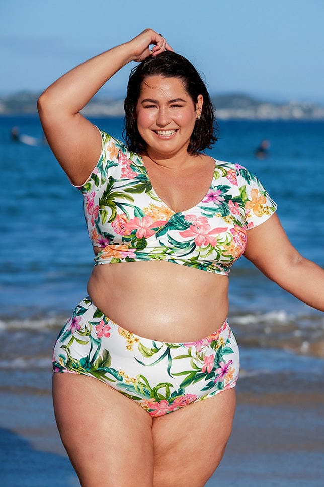 brunette woman wears white floral flattering high waisted bikini bottom at the beach